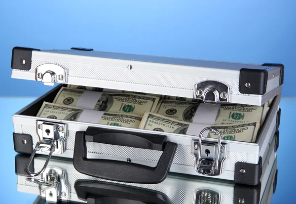 Koffer met 100 dollarbiljetten op blauwe achtergrond — Stockfoto