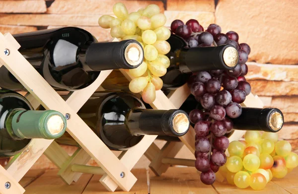 Bottles of wine placed on wooden stand on stone wall background — Stock Photo, Image