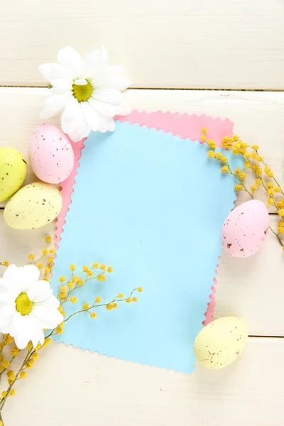 Tarjeta vacía con huevos de Pascua y flores de mimosa, sobre fondo de madera blanca Fotos de stock libres de derechos