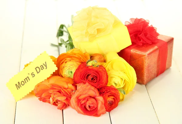 Ranunculus (buñuelos persas) y regalos para el día de las madres, sobre fondo de madera blanca — Foto de Stock