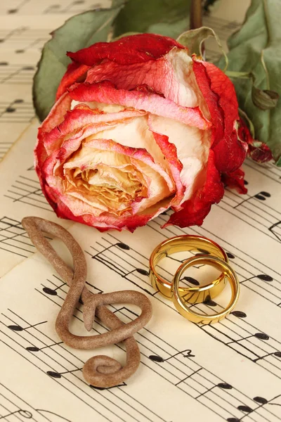 Clef triple, rosa y anillos de boda sobre fondo musical —  Fotos de Stock