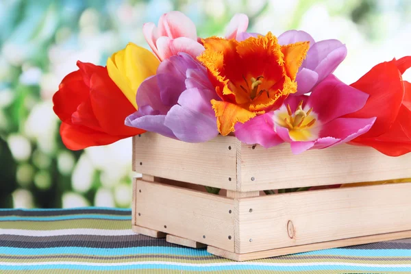 Schöne Tulpen in Strauß in Holzkiste auf Tisch auf hellem Hintergrund — Stockfoto
