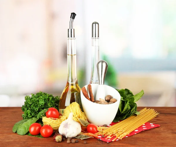 Composition of mortar, pasta and green herbals, on bright background — Stock Photo, Image