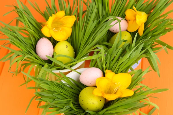 Paskalya yumurtaları kase çim üzerinde turuncu ahşap masa ile yakın çekim — Stok fotoğraf