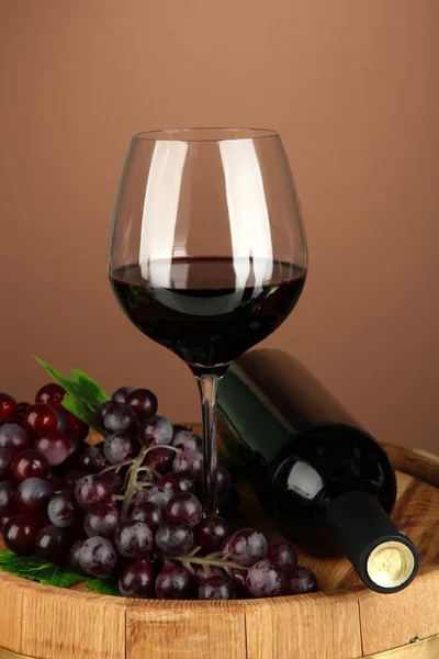 Composição da garrafa de vinho, copo de vinho tinto, uva no barril de madeira, no fundo da cor — Fotografia de Stock