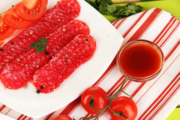 Leckere Salami auf Teller auf Holztisch in Großaufnahme — Stockfoto