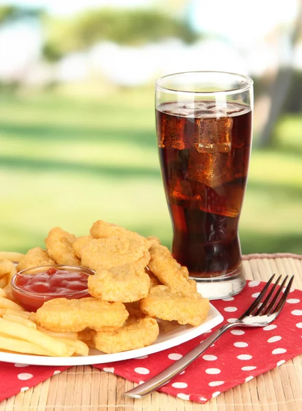 Fried chicken nuggets with french fries,cola and sauce on table in park — Stock Photo, Image