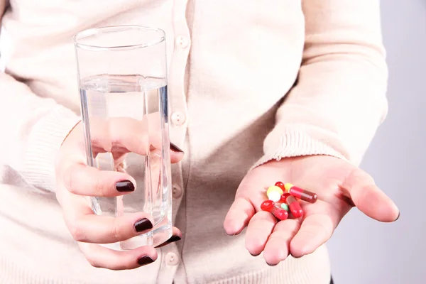 Mnoho pilulek a sklenici vody v ruce — Stock fotografie
