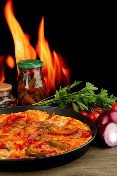 Tasty pepperoni pizza in pan with vegetables on flame background — Stock Photo, Image