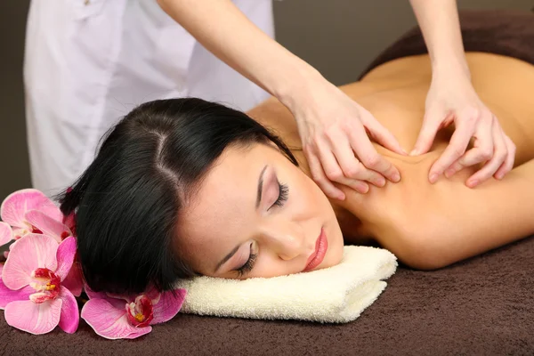 Bella giovane donna in salone spa ottenere massaggio con pietre spa, su sfondo scuro — Foto Stock