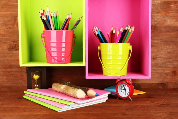 Colorful pencils in pails on shelves on wooden background — Stock Photo, Image