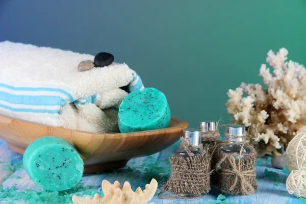 Olio spa, asciugamani candele su tavolo di legno su sfondo blu — Foto Stock