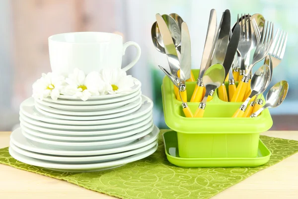 Lemezek, forks, kés, kanál és egyéb konyhai szerszám, a színes szalvéta, a világos háttér — Stock Fotó