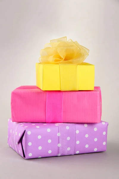 Bright gifts with bows on grey background — Stock Photo, Image