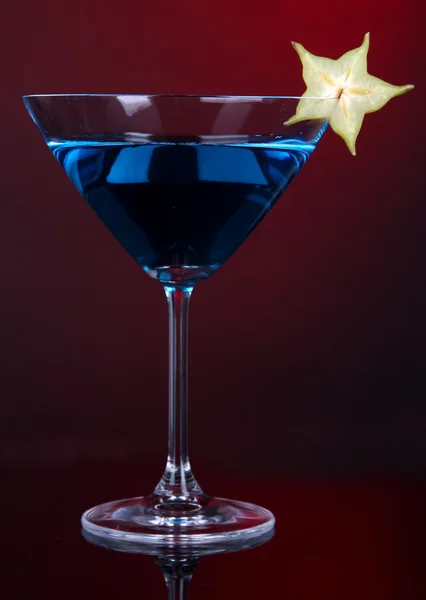 Blue cocktail in martini glass on dark red background — Stock Photo, Image