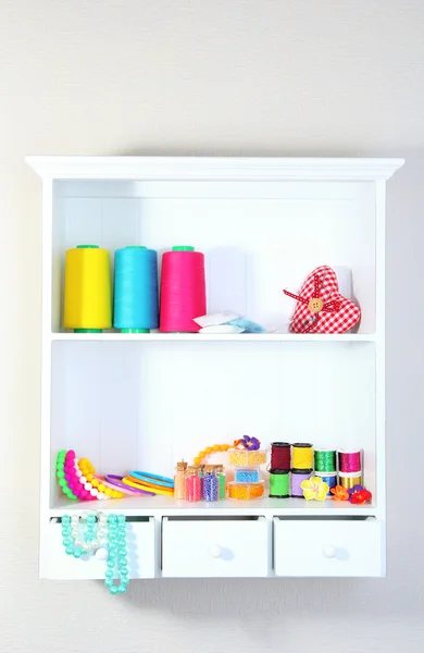 Beautiful white shelves with thread and material for handicrafts — Stock Photo, Image