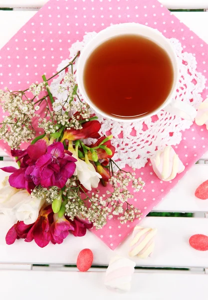 Beautiful composition with cup of tea and flowers on wooden picnic table close-up — Stock Photo, Image