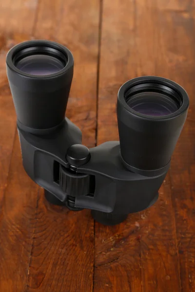 Black modern binoculars on wooden background — Stock Photo, Image