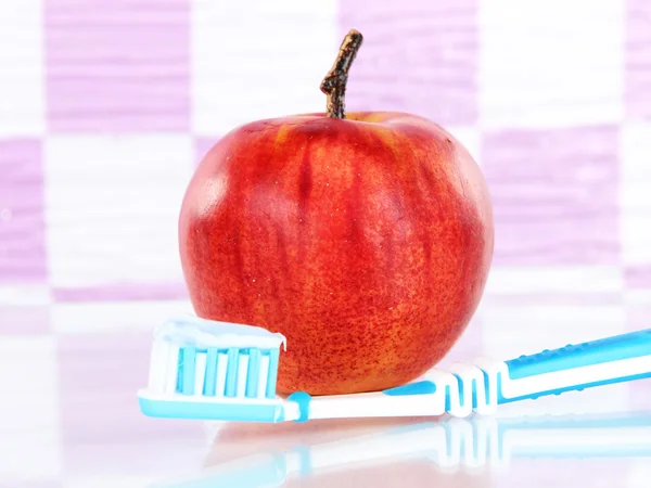 Maçã com uma escova de dentes na prateleira no banheiro — Fotografia de Stock