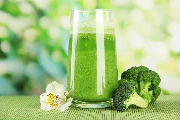 Vaso de jugo de brócoli, sobre estera de bambú, sobre fondo verde — Foto de Stock