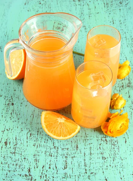 Gläser und Kanne Orangensaft auf blauem Holzgrund — Stockfoto