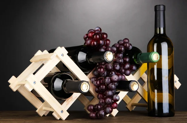 Botellas de vino colocadas sobre soporte de madera sobre fondo gris — Foto de Stock