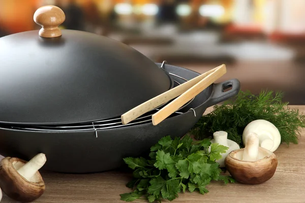 Preto wok pan e cogumelos na cozinha mesa de madeira, close-up — Fotografia de Stock