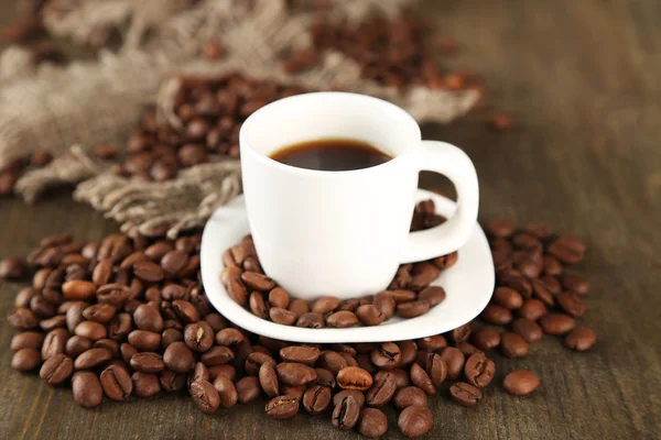 Cup of coffee and coffee beans on wooden background — Stock Photo, Image