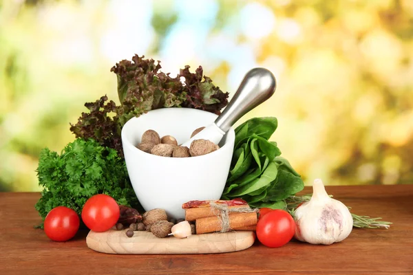 Komposition aus Mörser, Gewürzen, Tomaten und grünen Kräutern, auf hellem Hintergrund — Stockfoto