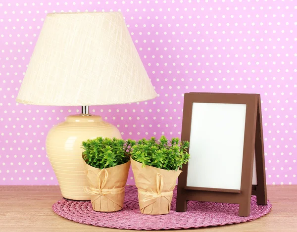 Marco de fotos marrón y lámpara sobre mesa de madera sobre fondo de pared lila — Foto de Stock