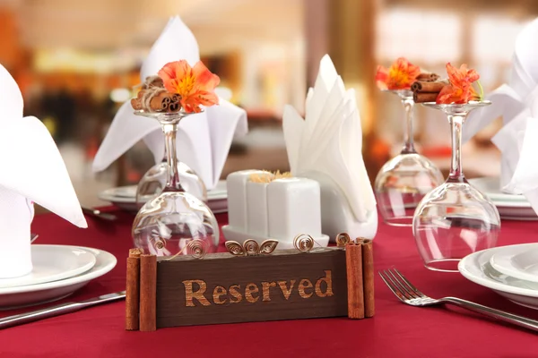 Reserved sign on restaurant table with empty dishes and glasses — Stock Photo, Image