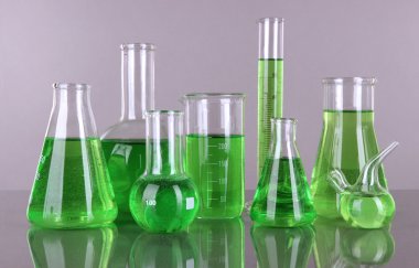 gri zemin üzerine yeşil sıvı ile test tüpleri