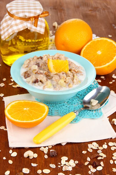 Harina de avena útil en un tazón con fruta en una mesa de madera — Foto de Stock