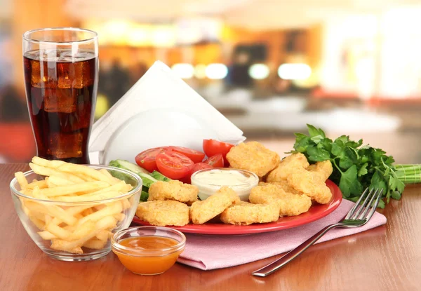 Smażone nuggets z kurczaka z warzywami, cola, frytkami i sosem na stole w kawiarni — Zdjęcie stockowe