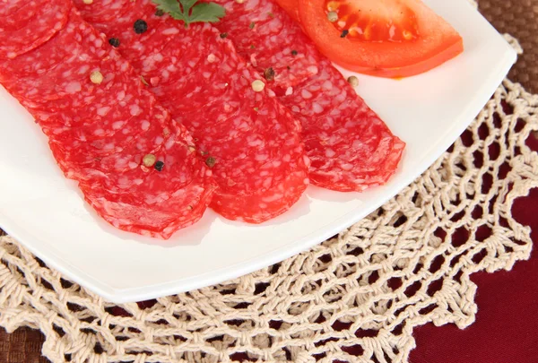 Tasty salami on plate on napkin close-up — Stock Photo, Image