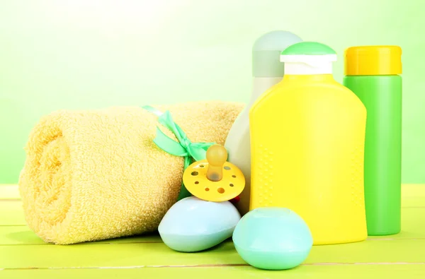 Cosméticos para bebés, jabón y toalla sobre mesa de madera, sobre fondo verde —  Fotos de Stock