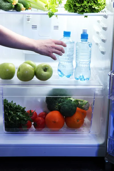 Рука женщины тянется за едой из холодильника, закрывается — стоковое фото