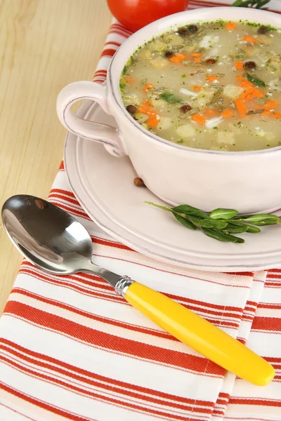 Nährende Suppe in rosa Pfanne auf Holztisch in Großaufnahme — Stockfoto