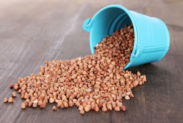 Overturned bucket with grains on wooden background — Stock Photo, Image