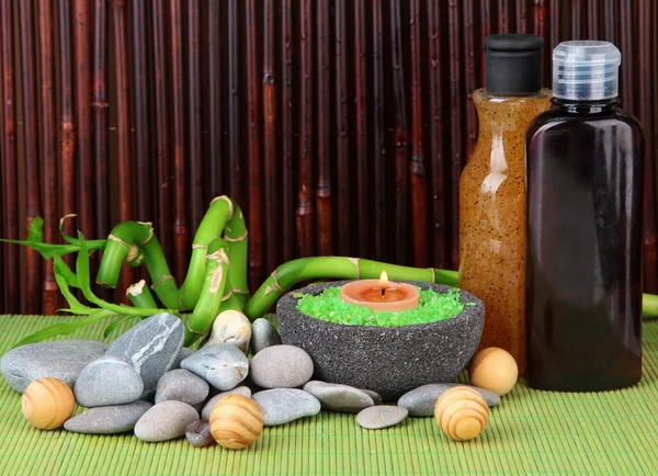 Bodegón con planta de bambú verde y piedras, sobre estera de bambú sobre fondo de color — Foto de Stock