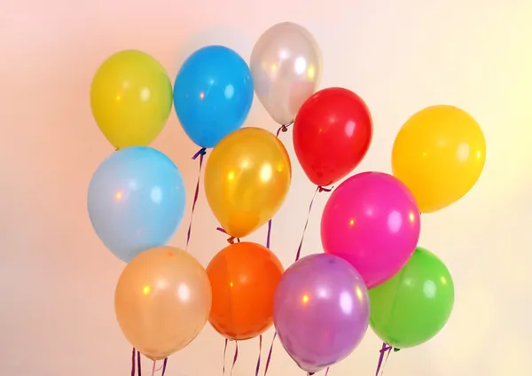 Viele helle Luftballons auf orangefarbenem Hintergrund — Stockfoto