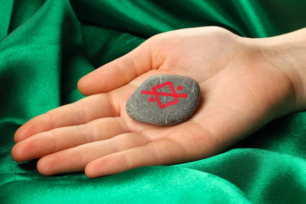 Fortune telling with symbols on stone in hand on green fabric background — Stock Photo, Image