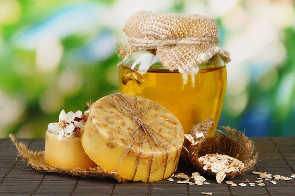 Sapone fatto a mano e ingredienti per la preparazione del sapone su tappetino di bambù, su sfondo verde — Foto Stock