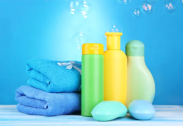 Cosméticos de bebê, toalhas e sabão na mesa de madeira, no fundo azul — Fotografia de Stock