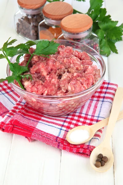 Schüssel mit rohem Hackfleisch mit Gewürzen auf Holztisch — Stockfoto