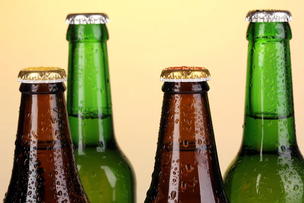 Coloured glass beer bottles on yellow background