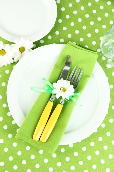 Cuchillo y tenedor envueltos en servilleta, en placa, sobre fondo de mantel de color — Foto de Stock