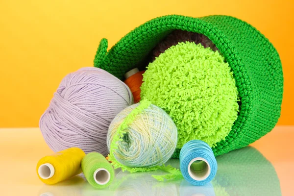 Colorful yarn for knitting in green basket on orange background — Stock Photo, Image