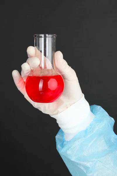 Glass tube with fluid in scientist hand during medical test on black background — Stock Photo, Image