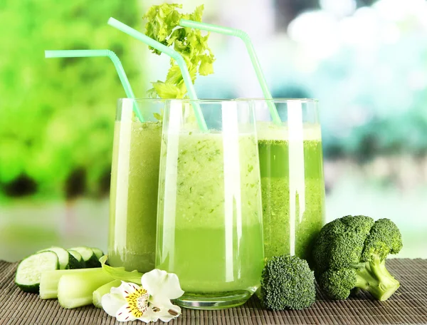 Glasses of vegetable juice, on bamboo mat, on green background — Stock Photo, Image